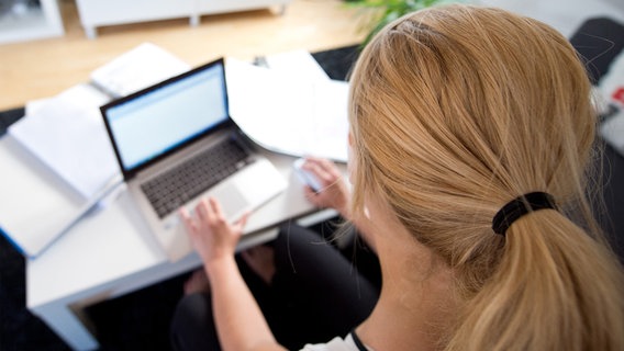 Eine Frau (der Kopf ist von hinten aus der Vogelperspektive zu sehen) sitzt an einem Laptop. © dpa-Bildfunk Foto: Daniel Naupold