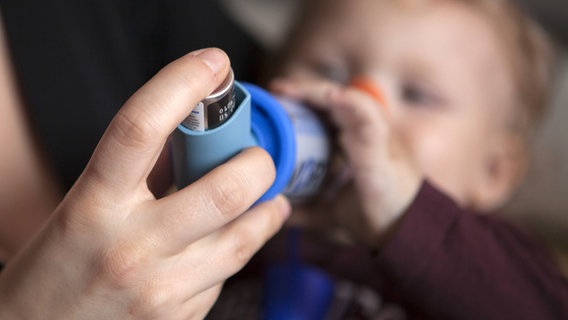 Eine Person lässt ein Kleinkind ein Spray inhalieren. © picture alliance/dpa Foto: Silvia Marks