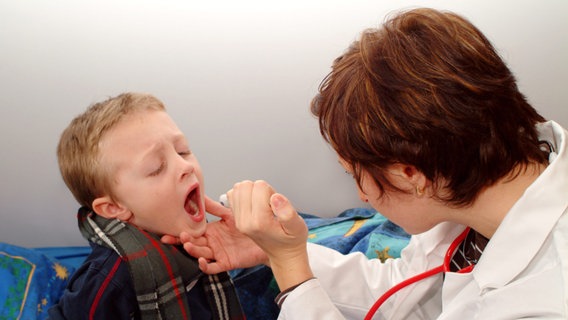 Eine Ärztin schaut einem kleinen Jungen in den Rachen. © picture alliance / Bildagentur-online 