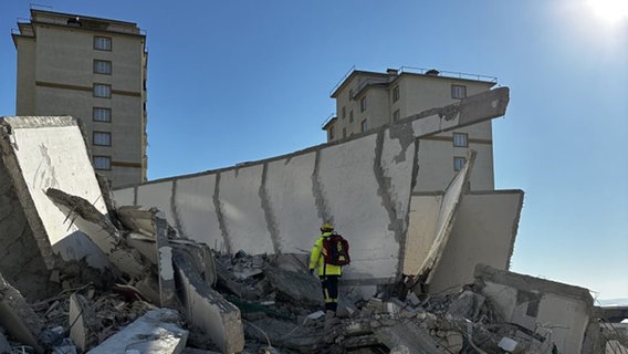Ein Helfer steht nach Erdbeben in der Türkei auf zertrümmerten Gebäuden. © @fire 