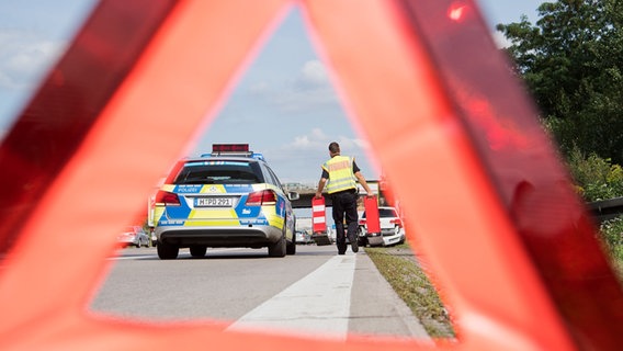Ein Polizist sichert eine Unfallstelle auf einer Autobahn.  Foto: Julian Stratenschulte
