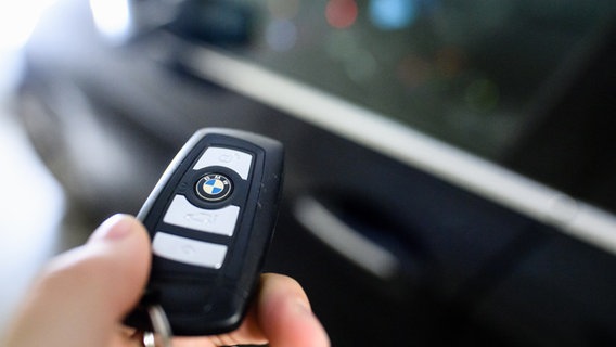 Ein Mann hält den Schlüssel eines BMW in der Hand. © Matthias Balk/dpa 