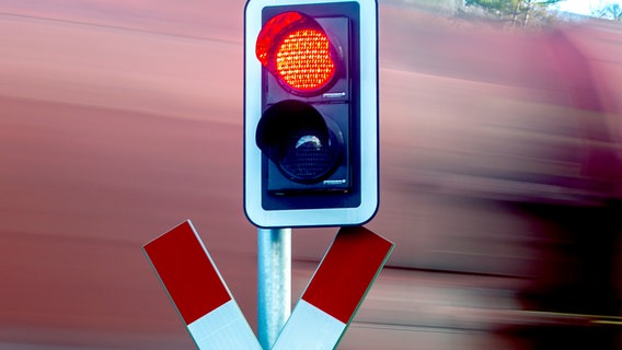 Ein Zug fährt an einem Bahnübergang mit Andreaskreuz vorbei. © picture alliance / | R4223 