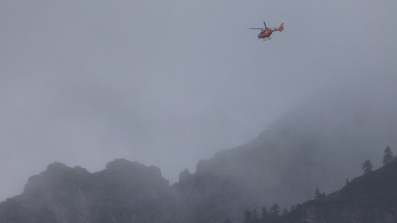 Rettungskräfte suchen am Hochkalter mit einem Hubschrauber nach einem vermissten Bergsteiger. © Bergwacht Ramsau/dpa 