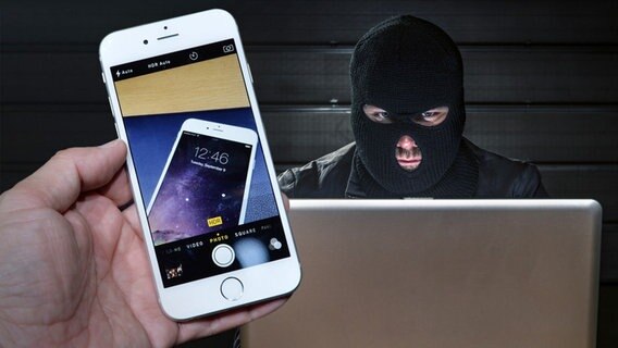 Maskierter Betrüger sitzt hinter einem Laptop, davor eine Hand mit einem IPhone (Bildmontage) © imago/AFLO, fotolia Foto: AFLO, lbtn