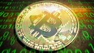 Eine Münze mit dem Bitcoin-Logo mit einem binären Zahlencode (grünes Licht) überzogen. © picture alliance/chromorange Foto: Christian Ohde