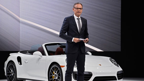 Der Vorstandsvorsitzende der Porsche AG, Oliver Blume, steht neben einem Porsche auf einer Bühne. © dpa - Bildfunk Foto: LARRY W. SMITH