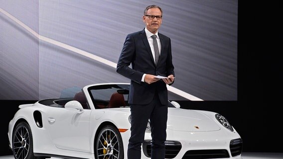 Der Vorstandsvorsitzende der Porsche AG, Oliver Blume, steht neben einem Porsche auf einer Bühne. © dpa - Bildfunk Foto: LARRY W. SMITH