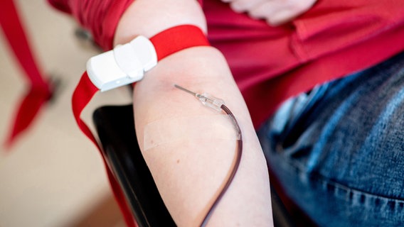 Blut läuft während einer Blutspende vom Arm einer Spenderin durch eine Nadel in einen Beutel. © picture alliance Foto: Hauke-Christian Dittrich