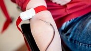 Blut läuft während einer Blutspende vom Arm einer Spenderin durch eine Nadel in einen Beutel. © picture alliance Foto: Hauke-Christian Dittrich