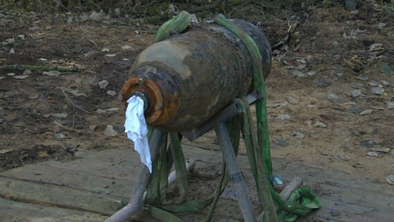 Eine entschärfte Bombe mit weißen Tüchern an der Zündöffnung liegt auf einem Gestell.  
