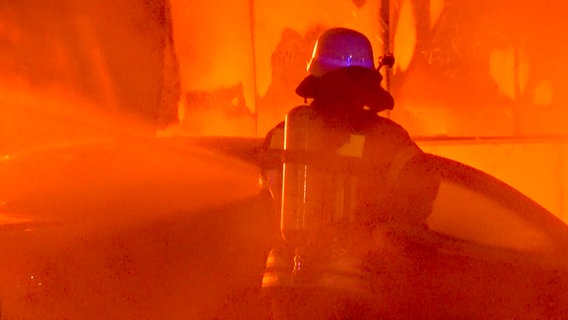 Ein Feuerwehrmann löscht eine brennende Scheune. © Nord-West-Media TV 