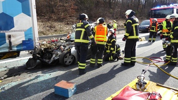 Einsatzkräfte der Feuerwehr stehen an einer Unfallstelle auf der A7. © dpa/Feuerwehr Kassel 