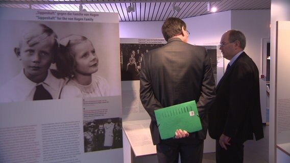 Zwei Männer stehen in einer Ausstellung über die verschleppten Kinder der Attentäter des 20. Juli. © NDR 