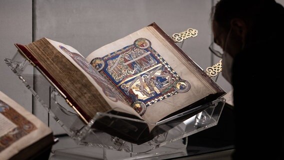 Ein Mann betrachtet das Evangeliar Heinrichs des Löwen und Mathildes von England. Ein Mann betrachtet das Evangeliar Heinrichs des Löwen und Mathildes von England. © Picture Alliance Foto: Swen Pförtner
