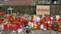 Auf der Straße aufgestellte Kerzen, Blumen und ein Teddybär. Im Hintergrund ein Pappschild mit der Aufschrift "Warum?" © dpa - Bildfunk Foto: Christoph Mischke