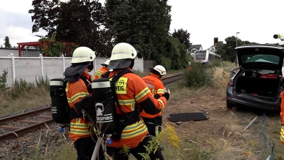 Einsatzkräfte der Feuerwehr stehen vor einer Unfallstelle an einem Bahnübergang. © NonstopNews 