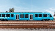 Ein mit Wasserstoff betriebener Brennstoffzellenzug steht auf Bahngleisen. © evb Foto: René Frampe