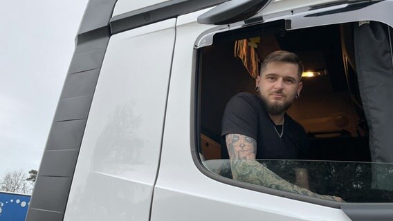Lkw-Fahrer Lukasz Szynkarek schaut aus dem Führerhaus seines Lastwagens. © NDR Foto: Michael Brandt