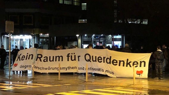 Demonstranten stehen mit einem Banner mit der Aufschrift: "Kein Raum für Querdenken" vor der Polizei. © NDR Foto: Jens-Walter Klemp