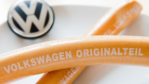 Eine noch verpackte VW-Currywurst mit der Aufschrift "Volkswagen Originalteil". © Julian Stratenschulte/dpa Foto: Julian Stratenschulte