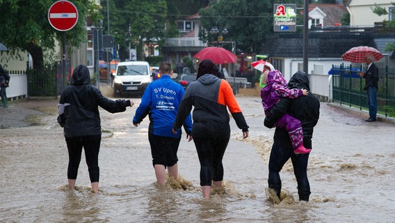 Menschen laufen auf einer überfluteten Straße in Bad Harzburg. © picture alliance/dpa Foto: Swen Pförtner