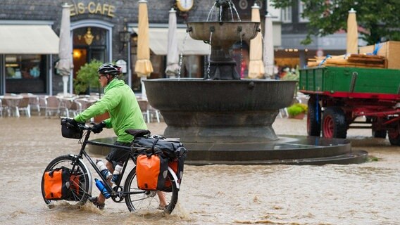 Ein Mann schiebt ein Fahrrad durch die überflutete Altstadt von Goslar. © picture alliance/dpa Foto: Swen Pförtner