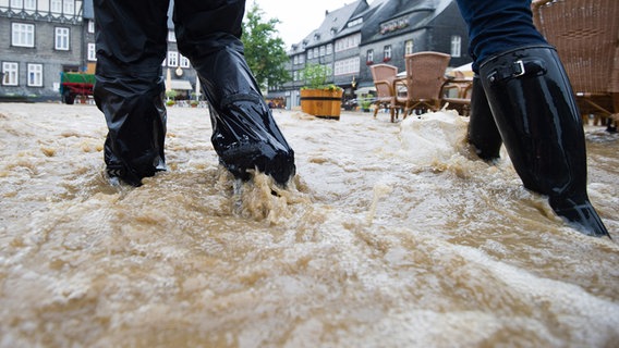 Menschen gehen in Goslar über den gefluteten Marktplatz in der historischen Altstadt. © picture alliance/dpa Foto: Swen Pförtner