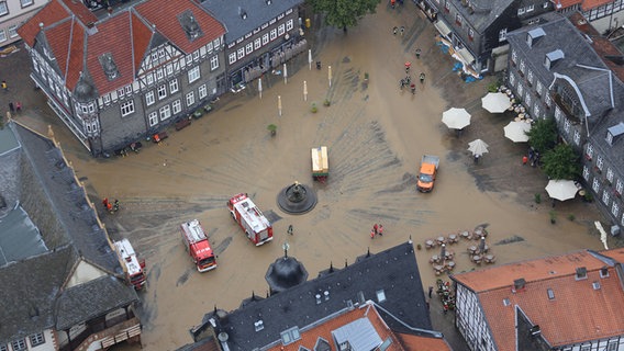 Feuerwehrfahrzeuge stehen auf dem schlammbedeckten historischen Marktplatz von Goslar nachdem Wassermassen den Platz zuvor überschwemmt hatten. © picture alliance/dpa Foto: Stefan Rampfel