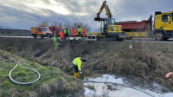 Reinigungskräfte entfernen Diesel aus einem Graben neben der Autobahn 39. © NDR Foto: Michael Brandt