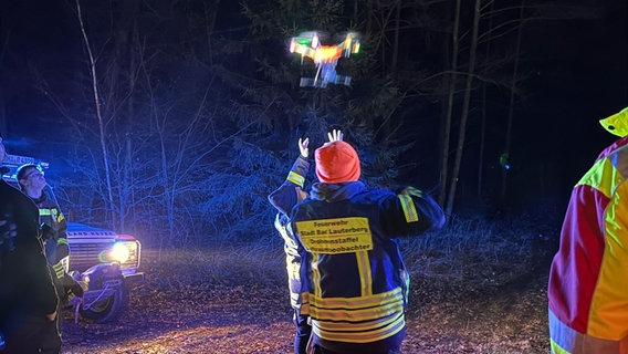 Feuerwehrmann mit roter Mütze lässt eine Drohne im Wald im Harz fliegen © SEG ASB Bad Lauterberg Foto: Amelie Cuers