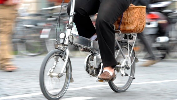 Eine Frau mit schwarzer Hose fährt auf einem silbernen Elektrofahrrad. © dpa Foto: Tobias Hase