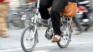 Eine Frau mit schwarzer Hose fährt auf einem silbernen Elektrofahrrad. © dpa Foto: Tobias Hase