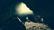 Sonnenlicht dringt über eine Deckenöffnung in die dunkle Einhornhöhle im Harz. © NDR Foto: Jens Klemp