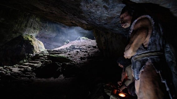 Neandertalerfiguren stehen an der Einhornhöhle in der "Blauen Grotte". © picture alliance Foto: Swen Pförtner
