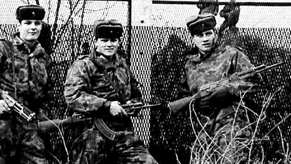 Eine Schwarzweißfotografie zeigt drei bewaffnete Soldaten, vor einem Grenzzaun. © NDR Foto: Hermann Pröhl