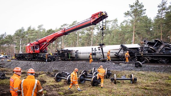 Mitarbeiter der Deutschen Bahn arbeiten an der Einsatzstelle nahe Gifhorn. Ein Kesselwagen wird mittels Schienendrehkran  geborgen. © Moritz Frankenberg/dpa Foto: Moritz Frankenberg/dpa