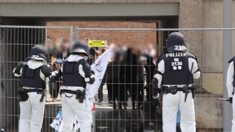 Polizisten stehen vor einem Haus.  