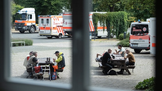 Bürger sitzen auf Bänken vor einem Evakuierungszentrum. © dpa-Bildfunk Foto: Swen Pförtner/dpa