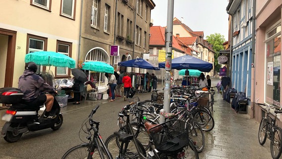 Passanten und viele angeschlossene Fahrräder in einer kleinen Straße in Göttingen. © NDR Foto: Jens-Walter Klemp