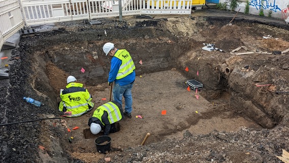 Arbeiter stehen in einer Ausgrabungsstelle auf dem Göttinger Wochenmarktplatz. © NDR Foto: Frederik Schulz-Greve