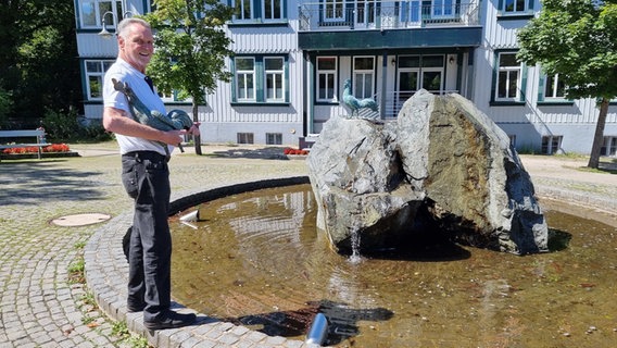 Klaus Elders, Stifter des neuen und alten Bronze-Hahns, steht mit dem vor vier Jahren gestohlenen Hahn vor dem Brunnen, auf dem bereits ein neuer Hahn aus Bronze befestigt ist. Klaus Elders, Stifter des neuen und alten Bronze-Hahns, steht mit dem vor vier Jahren gestohlenen Hahn vor dem Brunnen, auf dem bereits ein neuer Hahn aus Bronze befestigt ist. © dpa-Bildfunk Foto: Fernando Martinez/dpa