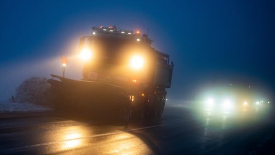 Ein Räumfahrzeug ist bei Dunkelheit auf einer verschneiten Straße im Harz unterwegs. © dpa-Bildfunk Foto: Swen Pförtner