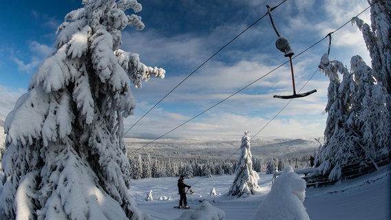 Ein Snowboarder lässt sich im Skigebiet am Sonnenberg mit einem Schlepplift den Berg hochziehen. © Swen Pförtner/dpa Foto: Swen Pförtner/dpa