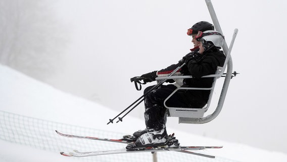 Wintersportler sitzen mit Skiern im Lift am Matthias-Schmidt-Berg bei St. Andreasberg im Harz. © dpa-Bildfunk Foto: Swen Pförtner/dpa