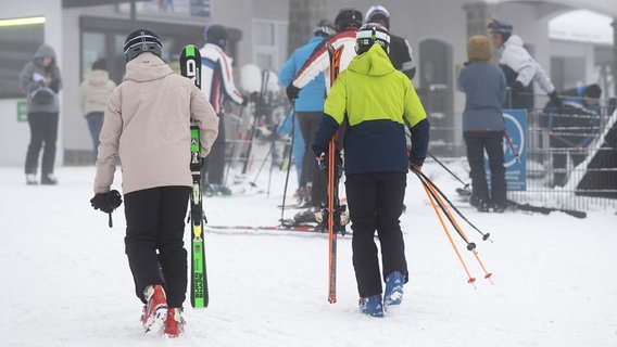 Wintersportler gehen mit ihren Skiern am Matthias-Schmidt-Berg in St. Andreasberg im Harz zum Lift. © dpa-Bildfunk Foto: Swen Pförtner/dpa