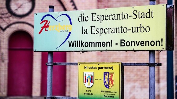 Ein Schild mit der Aufschrift "Herzberg die Esperanto-Stadt" ist am Bahnhof von Herzberg zu sehen. © dpa Foto: Swen Pförtner