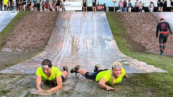 Die Göttinger Polizeipräsidentin Tanja Wulff-Bruhn (re.) und eine andere Teilnehmerin des Great Barrier Run in Göttingen landen am Ende einer Wasserrutsche im matschigen Gras. Die Göttinger Polizeipräsidentin Tanja Wulff-Bruhn (re.) und eine andere Teilnehmerin des Great Barrier Run in Göttingen landen am Ende einer Wasserrutsche im matschigen Gras. © Polizeidirektion Göttingen