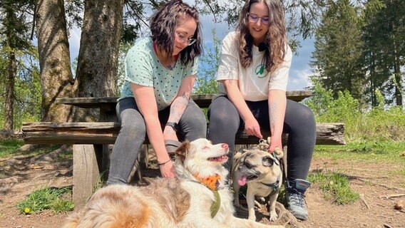 Jenny Steinbrecher und ihr Hund Cooper (links) und neben ihnen sitzen auf einer Bank Charlotte Jacobs und ihr Hund Charly. Jenny Steinbrecher und ihr Hund Cooper (links) und neben ihnen sitzen auf einer Bank Charlotte Jacobs und ihr Hund Charly. © NDR Foto: Marie-Luise Stiller