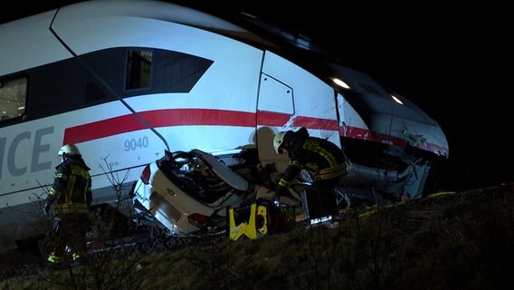 Feuerwehrleute an einem Zug unter dessen Triebwagen ein Auto eingekeilt ist. © HannoverReporter 